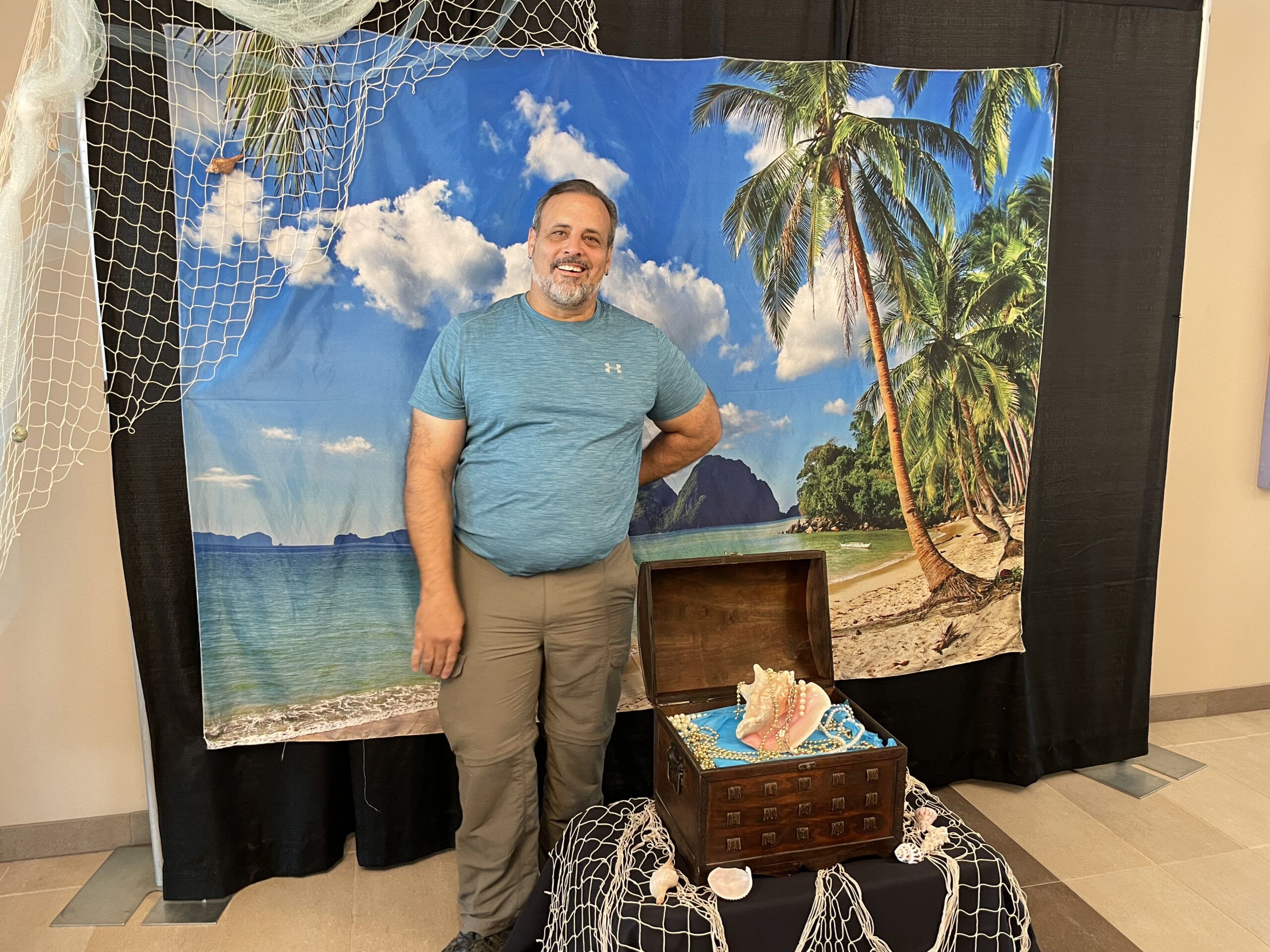Case manager Frank Rivas stands in front of an ocean view backdrop for CFI's photo booth at the 40th Anniversary Celebration on August 5th at the Colorado Mesa University Ballroom. 