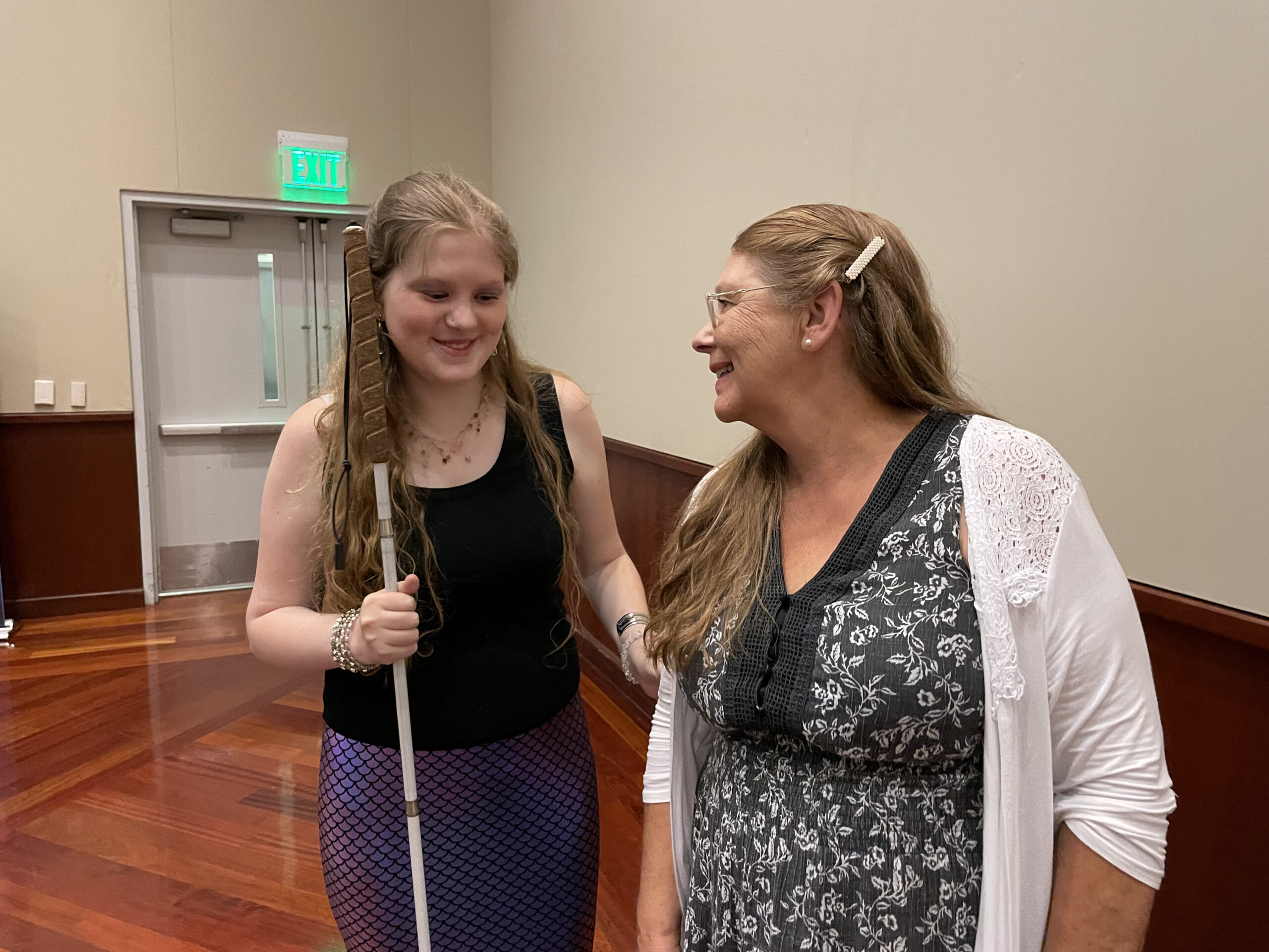Katherine Seaton with a white cane stands next to Joanne Stamp low vision program manager.